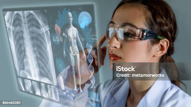 Young Female Doctor Looking At Hologram Screen Electronic Medical Record Smart Glasses Medical Technology Concept Stock Photo - Download Image Now