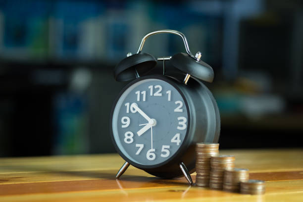 istock Alarm clock and step of coins stacks on working table, time for savings money concept. 864465492