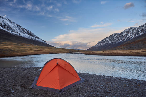 istock An orange tent near a river in the Mountains 864473628