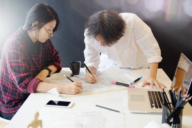 istock Architect team working on blueprint, Two colleagues interior designer discussing data on blueprint on table for architectural project in office. 864474870
