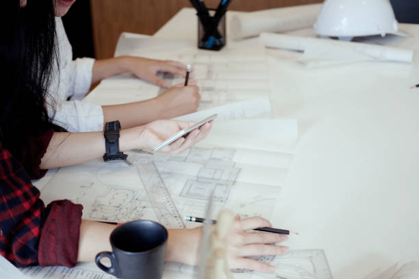 istock Architect team working on blueprint, Two colleagues interior designer discussing data on blueprint on table for architectural project in office. 864474880