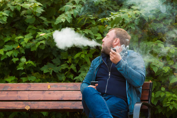 istock Young man smokes tobacco pipe in park 864475500