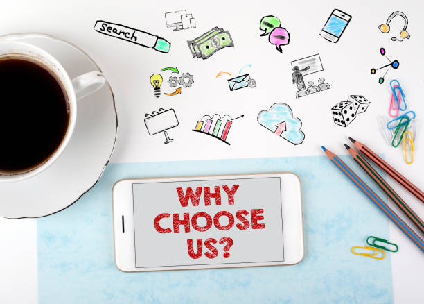 istock Why Choose Us. Mobile phone and coffee cup on a white office desk 864476606