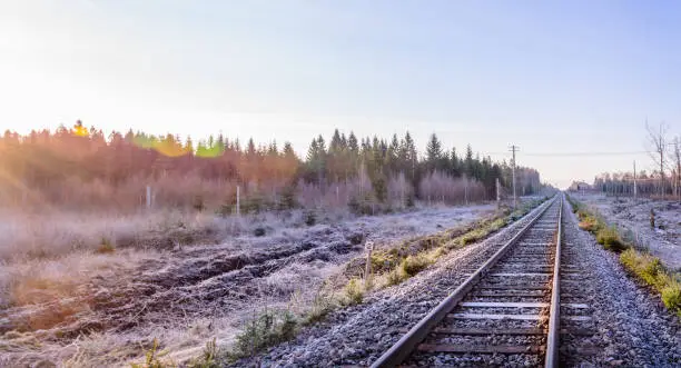 Frosty morning sunrise at the traintracks leading into the unknown distance in sweden - scandinavia