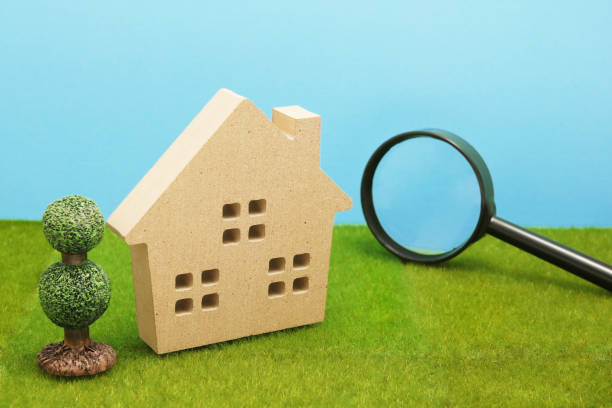 istock House and magnifying glass on green grass. 864482954