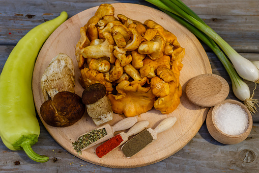 Chanterelle mushrooms and boletus edulis with ingredients for cooking on wooden plate