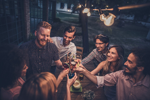 Large group of happy people having fun while toasting with alcohol on a night party.