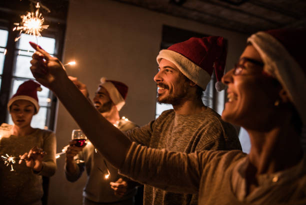 istock Happy friends with Santa's hats having fun while using sparklers on Christmas party. 864491474