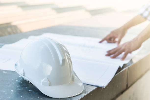istock The white safety helmet with the man verify blueprint for his project 864492876