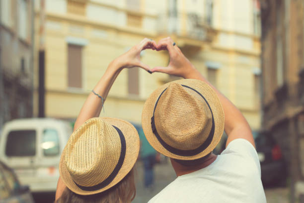 istock Couple in love making heart shape with hands outdoors.Focus on hat. 864493358
