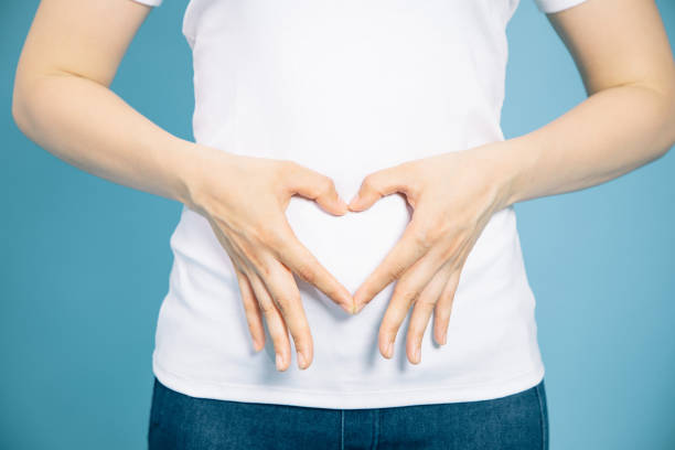 jovem que faz uma forma de coração por as mãos na barriga. - adult abdomen blue the human body - fotografias e filmes do acervo