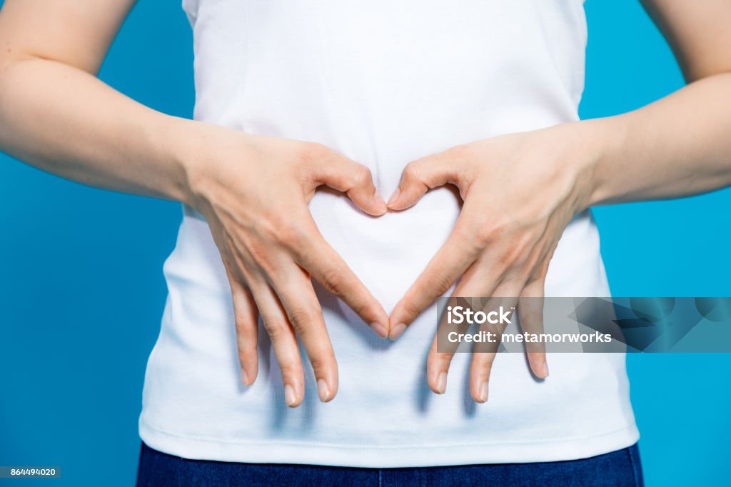 jeune femme qui fait une forme de coeur par les mains sur le ventre. - Photo de Abdomen libre de droits