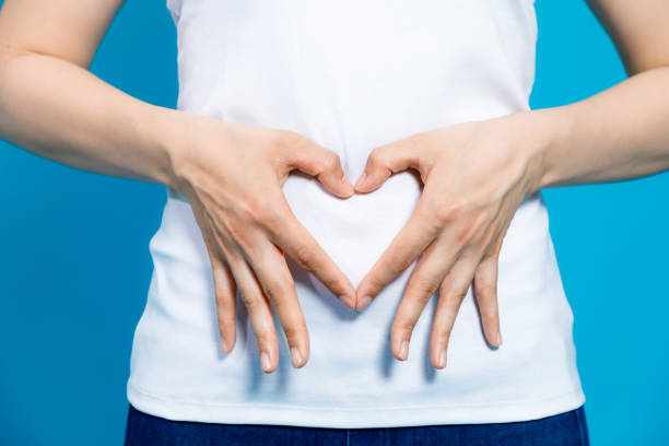 jovem que faz uma forma de coração por as mãos na barriga. - adult abdomen blue the human body - fotografias e filmes do acervo