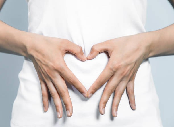 young woman who makes a heart shape by hands on her stomach. young woman who makes a heart shape by hands on her stomach. lactic acid stock pictures, royalty-free photos & images