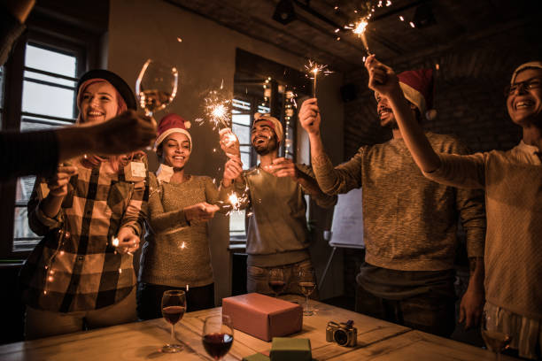 istock Group of young happy people having fun while using sparklers on New Year's office party. 864494652