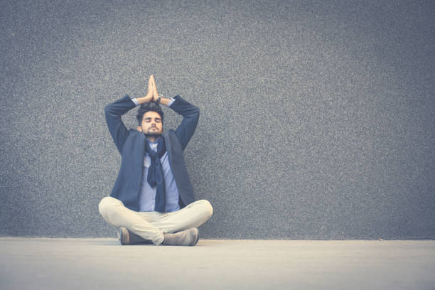 istock Businessman with closed eyes practicing yoga on sidewalk. Space for copy. 864495754