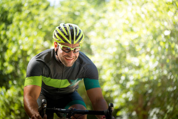 istock Smiling young man riding bicycle against trees 864495796