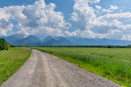 Driving through mountains on dirt road near a farm. Country road, grain,Carphatian mountains and blue sky.