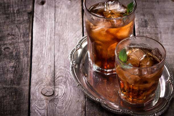 glas cola, eistee oder mit würfel und minze garnieren, auf holztisch, alkohol trinken - glass ice tonic water frozen stock-fotos und bilder
