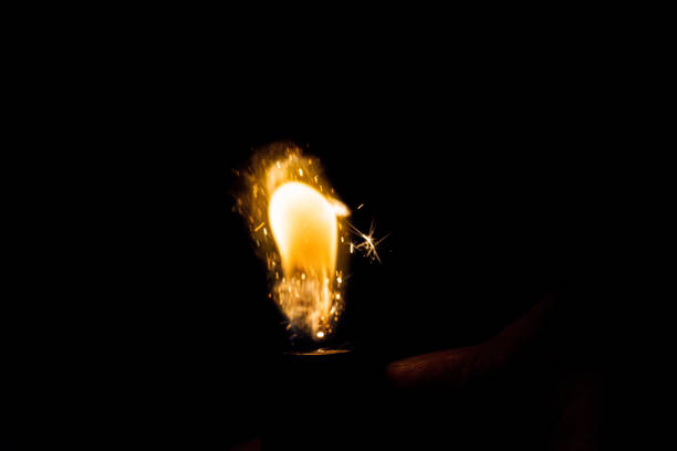 istock Close up view of real sparking light from lighter in dark black background 864509302