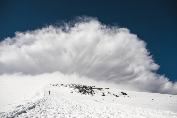 Stormy clouds surging above the snow-capped mountain Elbrus at sunset