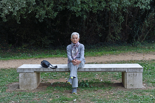 senior woman sitting alone on a bench in a park