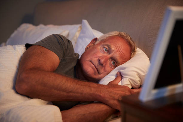 hombre senior triste tumbado en la cama mirando el marco de la foto - men mental illness loss despair fotografías e imágenes de stock