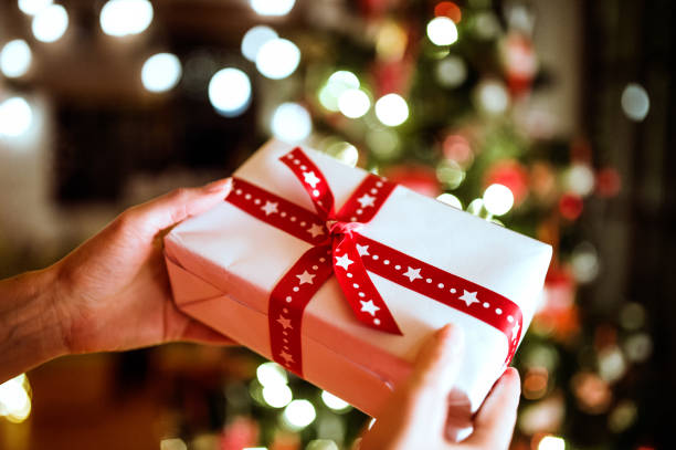 istock Unrecognizable woman in front of Christmas tree holding present 864518984
