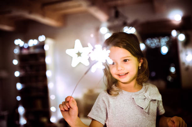 Little girl with a sparkler at Christmas time. Beautiful little girl with a sparkler at Christmas time at home. lighting fire cracker stock pictures, royalty-free photos & images