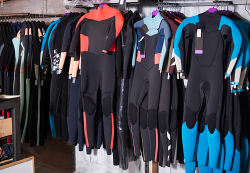 Image of colorful wetsuit hanging in the modern  shop for surfing