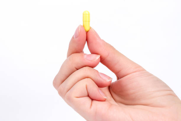 istock doctor's hand holds the yellow capsule close-up 864522690