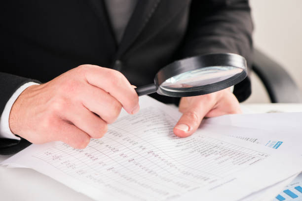 istock Businessman reading documents with magnifying glass concept for analyzing a finance 864525180