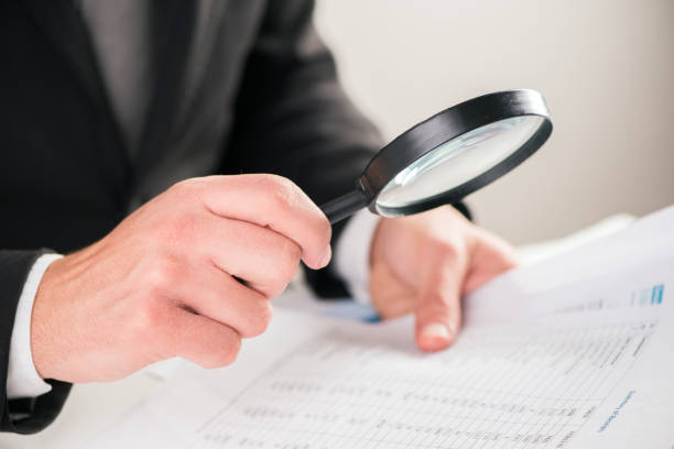 istock Businessman reading documents with magnifying glass concept for analyzing a finance 864525308