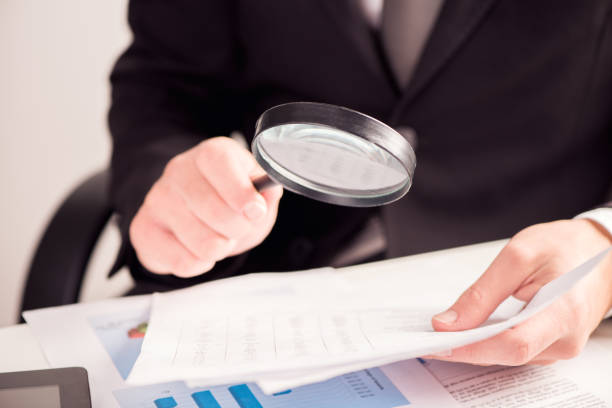 istock Businessman reading documents with magnifying glass concept for analyzing a finance 864525486