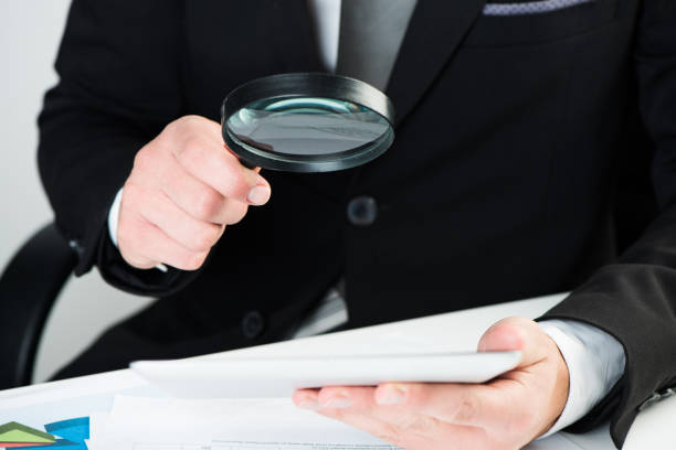 istock Businessman reading documents with magnifying glass concept for analyzing a finance 864525720