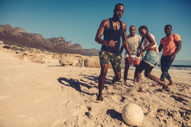 friends playing soccer on the beach - beach football imagens e fotografias de stock