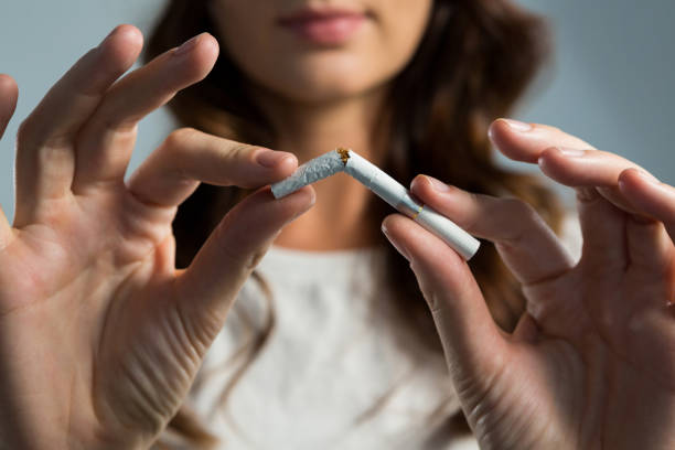 woman breaking cigarette against white background - breaking cigarette imagens e fotografias de stock