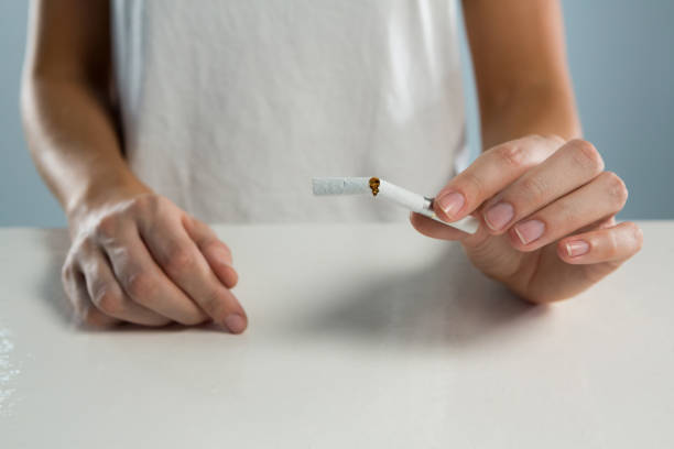 istock Woman breaking cigarette against white background 864527570