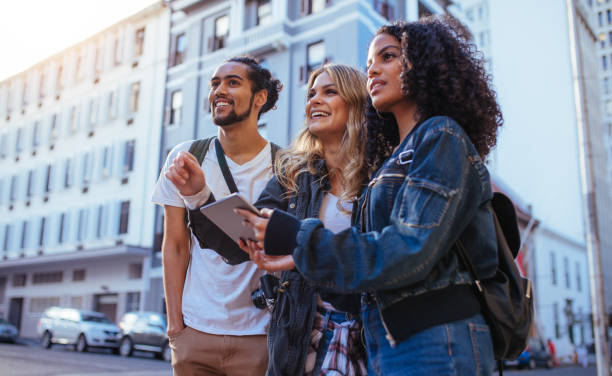 Group of friends exploring the city Tourists using navigation tools to explore the city. Man with two women friends exploring the city with travel accessories. three amigos stock pictures, royalty-free photos & images