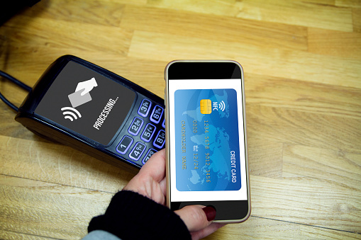 NFC Near field communication concept: Male hands using smart phone to made payment. All graphics are made up
