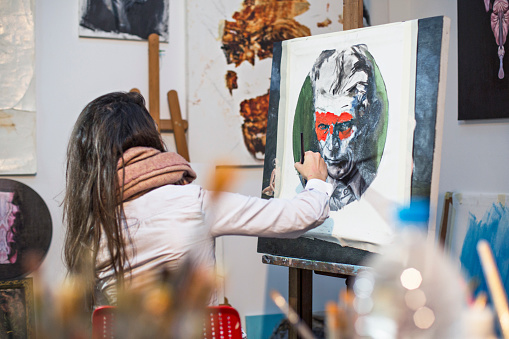 Female artist painting in her workshop studio.