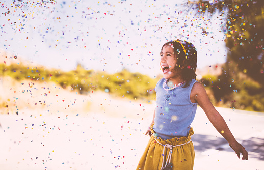 Joyful Asian girl playing at the park, having fun, laughing and throwing confetti