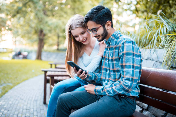 istock Young couple looking at something on a smartphone in the park 864535906