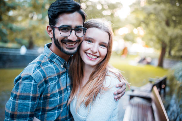 istock Young couple hugging in the park and looking at the camera 864535976