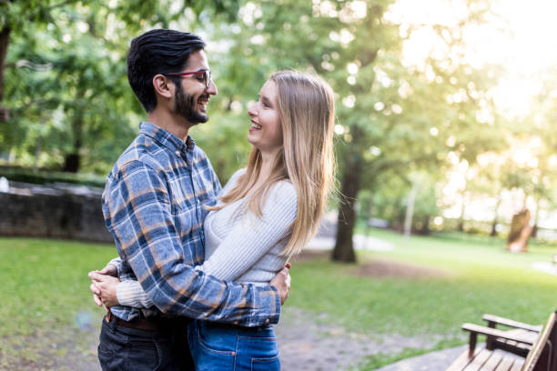 istock Young couple hugging in the park and looking at the camera 864535992