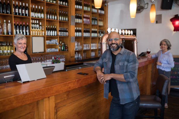 istock Man and senior waitress looking at camera in bar 864539568