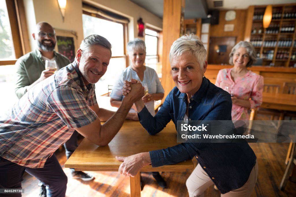 Happy friend arm wrestling each other Portrait of happy friend arm wrestling each other in a bar 40-44 Years Stock Photo