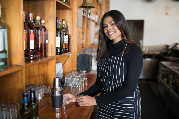 istock Smiling waitress standing at counter in bar 864540488