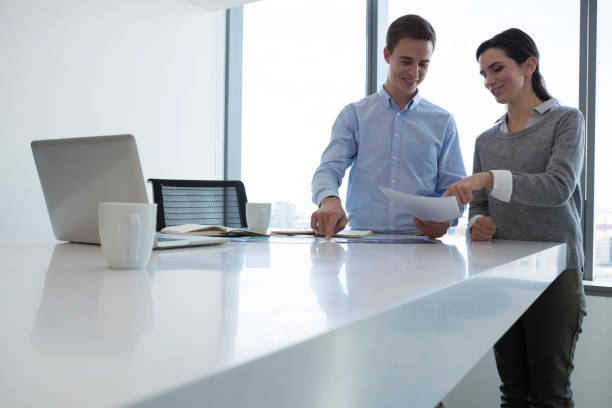 istock Male executive and female executive discussing over document 864541366