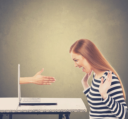 Surprise businesswoman with hand coming out of laptop screen for business deal